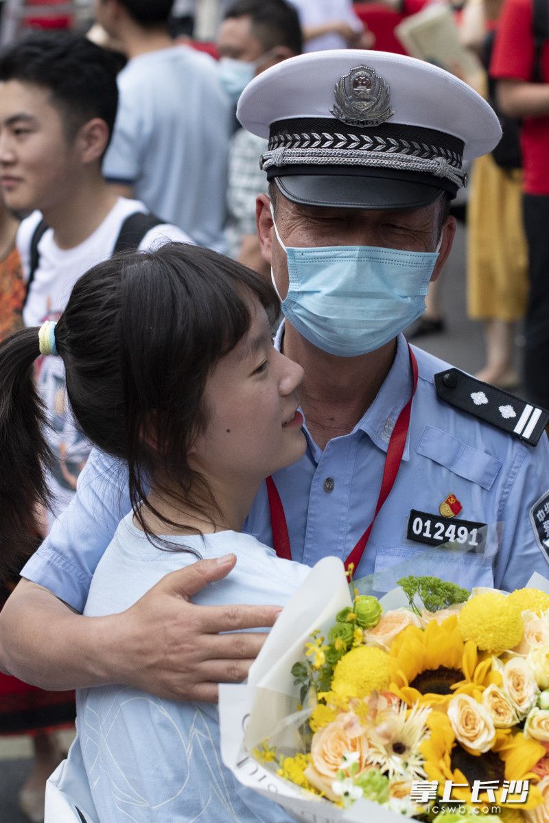 6月9日，长沙市一中考点，走出考场的女儿将花献给了正在执勤的交警爸爸范作。长沙晚报全媒体记者 黄启晴 摄