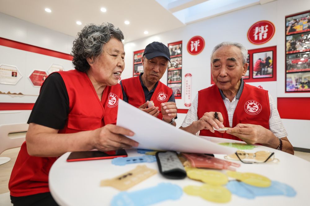 ↑8月18日，在牡丹社区志愿者之家，志愿者在制作小区树木、花坛、绿地居民认领牌。