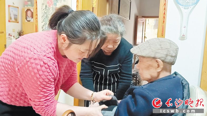 徐丽莎（左）给公公量血压。多年来，她一直悉心照料公公婆婆，视他们如亲生父母。长沙晚报通讯员 王国光 供图