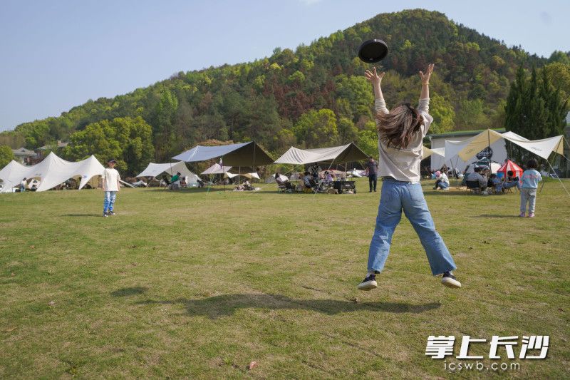 露营基地可以开展各类户外项目，一位家长与儿童正在进行飞盘游戏。 