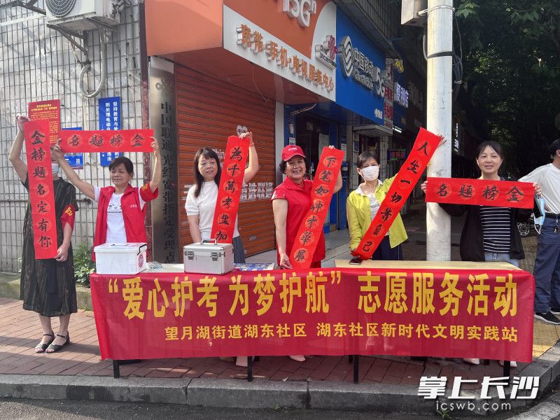 在麓山国际实验学校考点，志愿者们举着亲笔写下的对联，为考生加油呐喊。均为全媒体记者 刘俊 实习生 陈雯 摄影报道