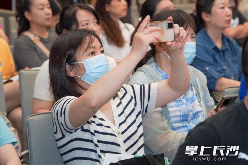 家长们在现场仔细聆听专家们的指导建议，并时不时地进行拍照记录。