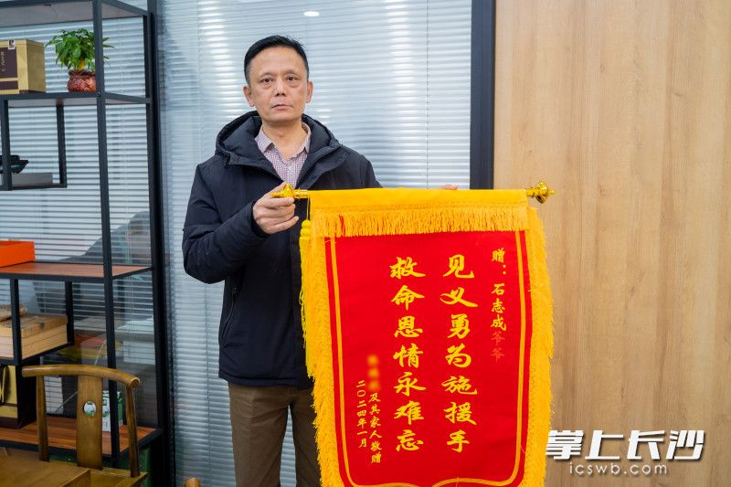 获救男孩的妈妈向石志成送上锦旗，表达感激之情。长沙晚报全媒体记者 刘晓敏 摄