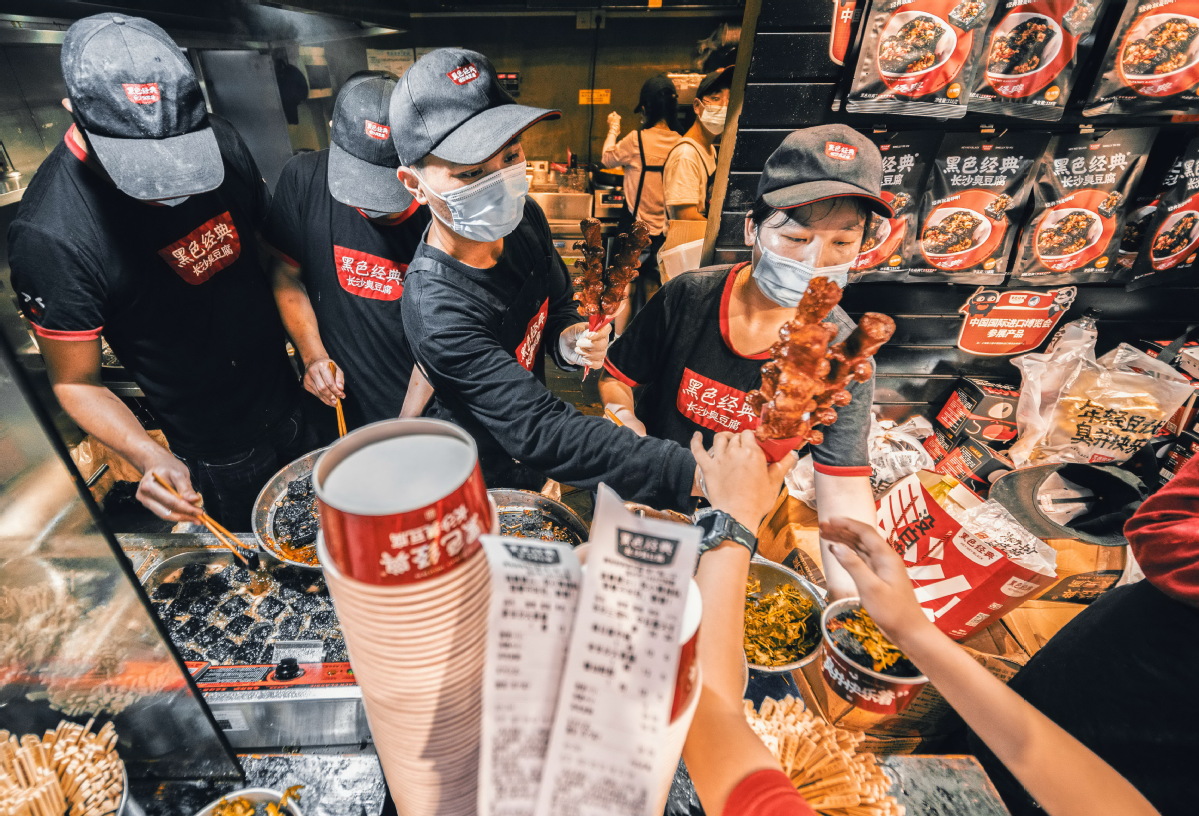 Employees prepare stinky tofu snacks at a Hey Hey Black store in Changsha, Hunan province, in May 2023. (Photo/China Daily)