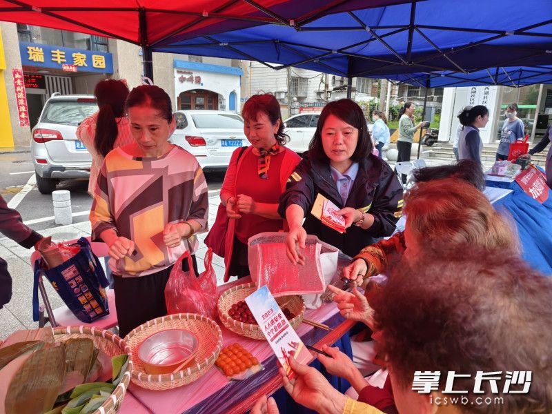 社区安全专干在包粽子现场向居民发放防火防电防溺水宣传单。均为社区供图