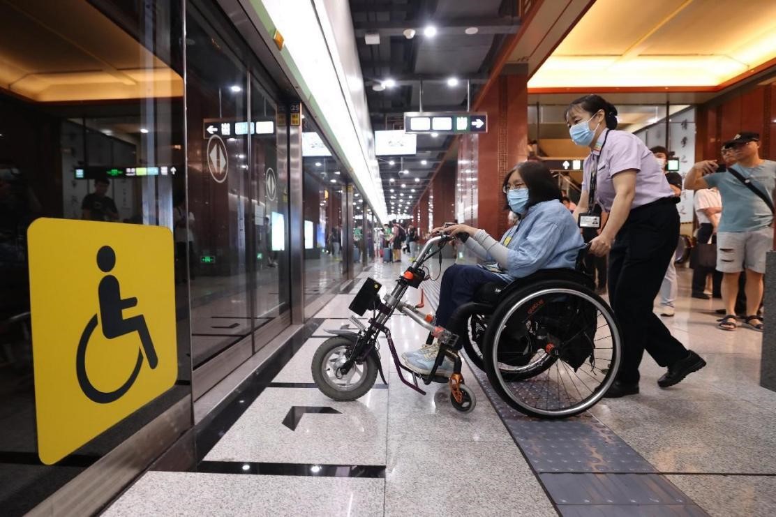 A metro staff member helps a passenger in a wheelchair board a train in Beijing. (People's Daily Online/Chen Xiaogen)