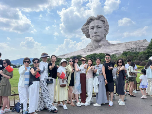 图为本次团队合影。于卓廷将个人仅有的半天休息空档，帮助游客预约协调并陪同来到橘子洲头，提供志愿讲解、拍摄等服务。