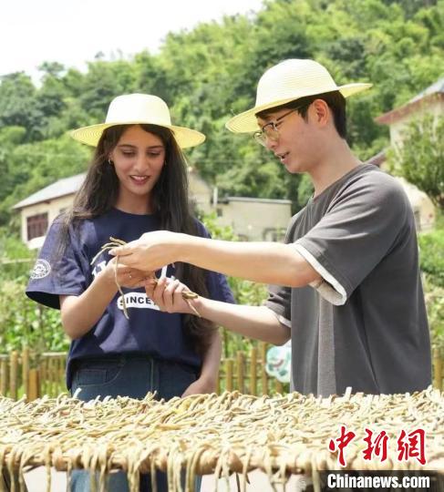 Yi Kai (R) shows an international student the organic green vegetables being dried. (Photo provided by HNUCM)