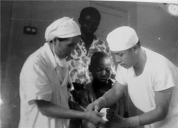 Li Hejun (right), professor of orthopedics with the Hunan hospital, puts a bandage on a patient suffering from bone fracture. He was a member of Hunan province's first medical team sent to support Africa in 1973. [Photo provided to China Daily]