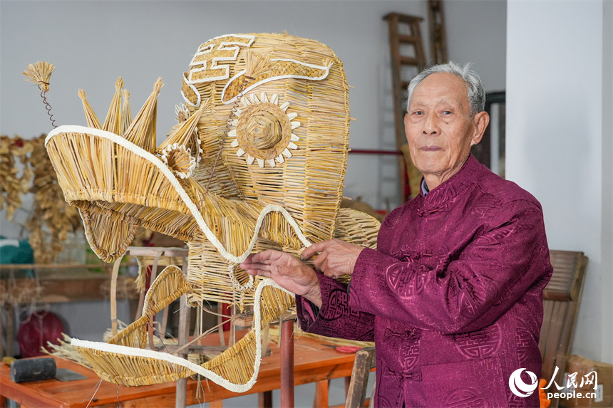 Photo shows Yu Fangze, an inheritor of the national intangible cultural heritage craft of weaving straw dragons, and a dragon head he wove in Hukou county, east China's Jiangxi Province. (People's Daily Online/Kong Wenjin)