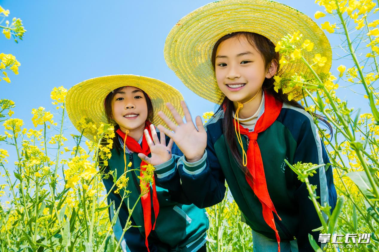 孩子们带着自制的“春天草帽”在花海中游玩。