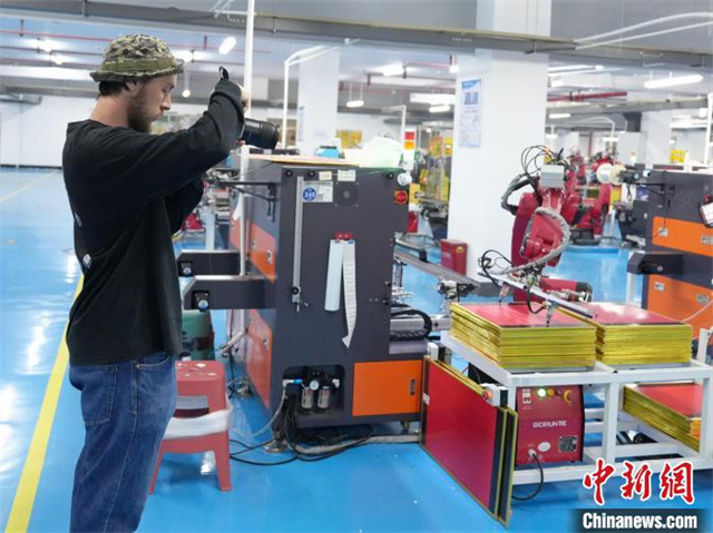 The photo shows a Russian photographer taking pictures of an automated fishing tackle plant. Photo/Yang Huafeng, Chinanews
