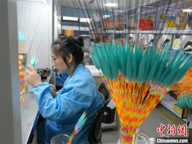 The photo shows a worker painting fishing floats. (Photo/Yang Huafeng, Chinanews) 
