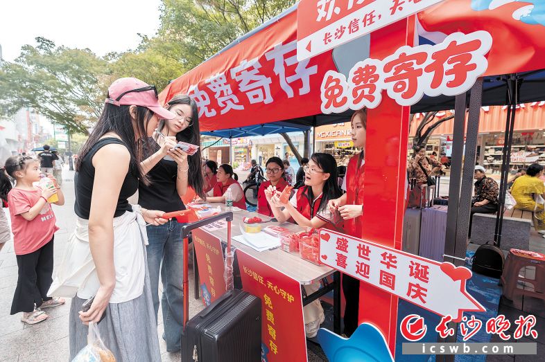 　　刘明珠（红衣志愿者右起第二位）正在为游客提供行李寄存服务。　　长沙晚报全媒体记者 陈飞 摄