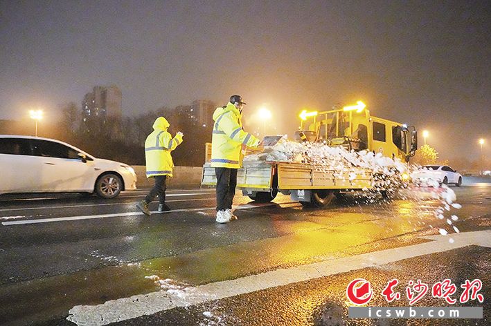 1月20日晚，在东二环高架桥上，市政工作人员正在给路面撒盐融雪，确保路面畅通。长沙晚报全媒体记者 邹麟 实习生 彭唯真 摄影报道