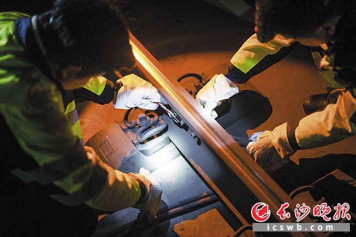 两人协作精准地完成铁轨上轨道电路的螺丝检修。
