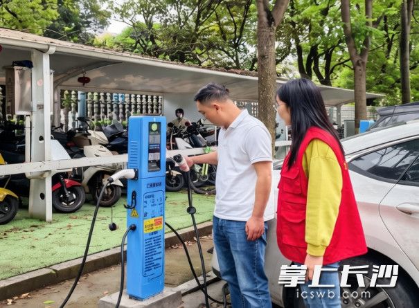 长沙县泉塘街道泉旭社区工作人员吴尚（左一）、罗畅正在逐个检查充电桩安装效果。