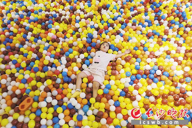 在万家丽国际MALL 的一处游乐园，一个孩子惬意地躺在五彩缤纷的海洋球里。