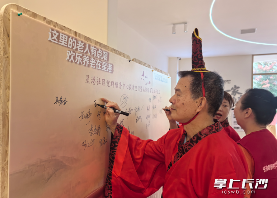 居民们纷纷在印有“这里的老人有点潮 欢乐养老在星港”的签名墙上签名打卡。